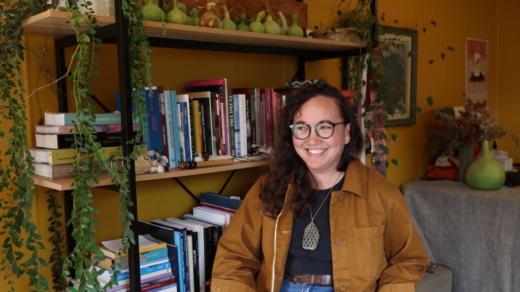 2026 TCA | NZSA Writers' Award Winner Matariki Williams sitting in front of bookcase smiling